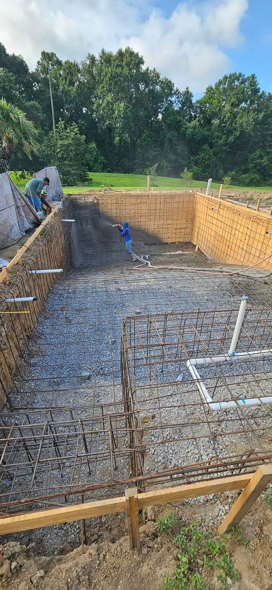 A swimming pool is being built in a dirt field.