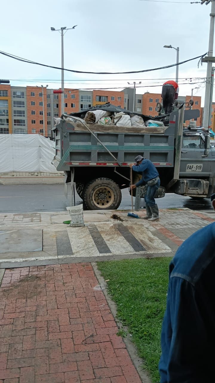 Un hombre está parado al lado de un camión de volteo al costado de la carretera.