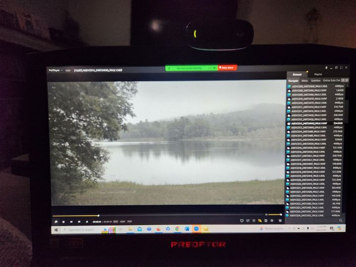 A laptop screen shows a video player with a misty lake scene and a chat/sidebar on the right.