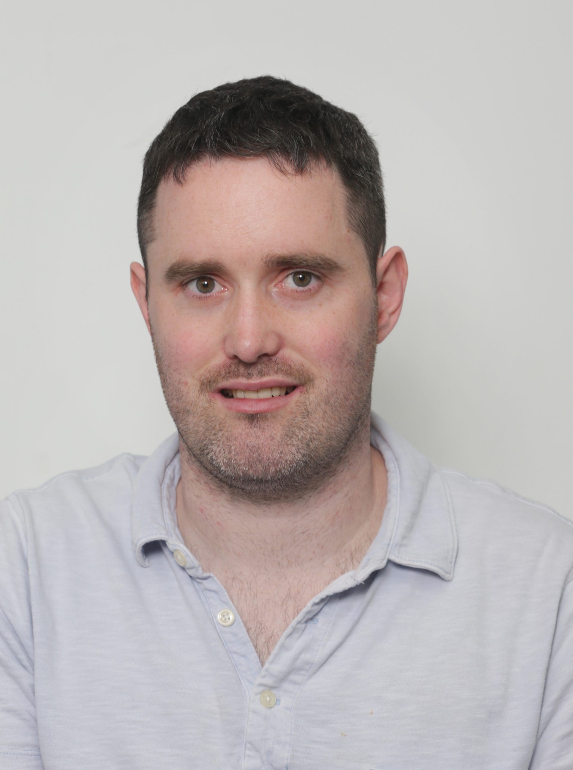 Head-and-shoulders portrait of a man in a light blue polo against a plain gray background