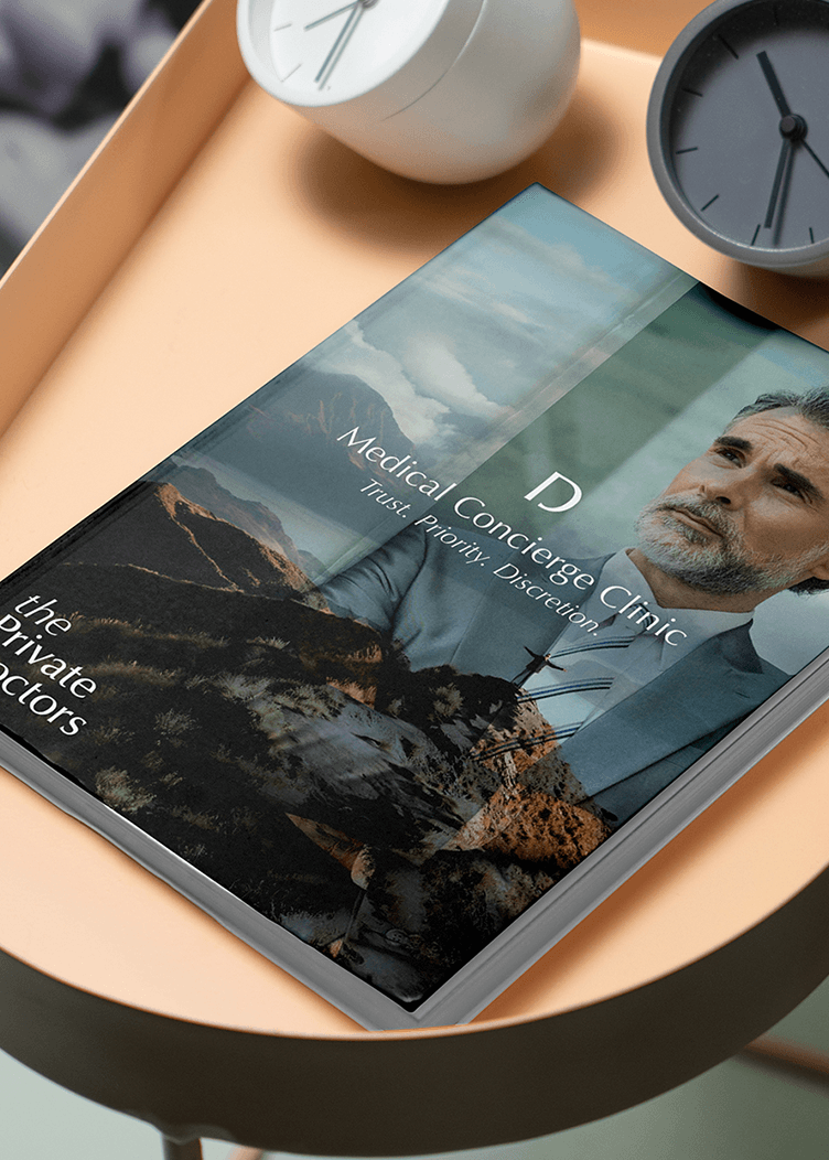 Magazine on a peach tray beside two modern clocks; cover shows a coastal landscape and a bearded man.