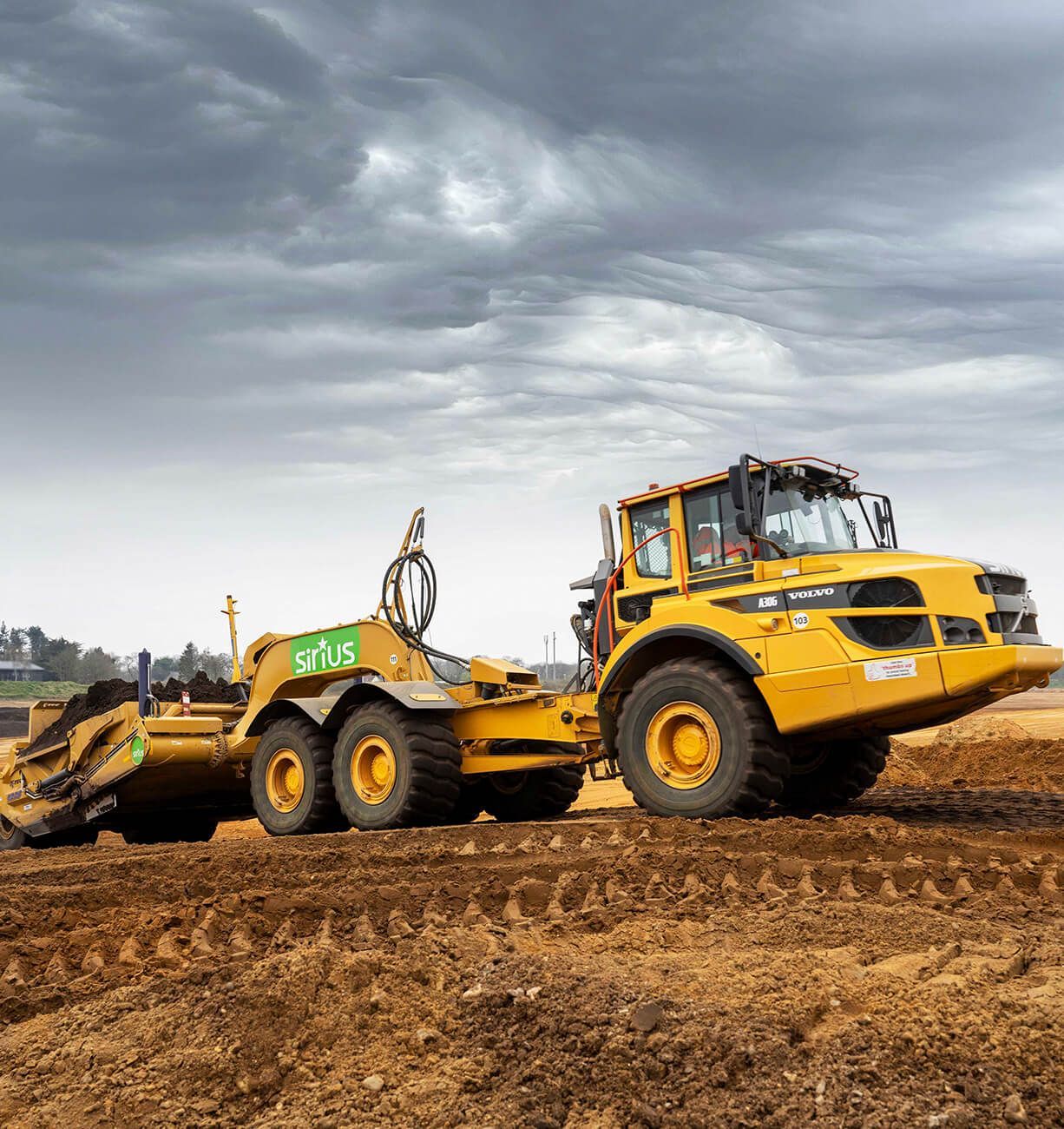 Yellow construction bulldozer on a muddy dirt site under a cloudy sky