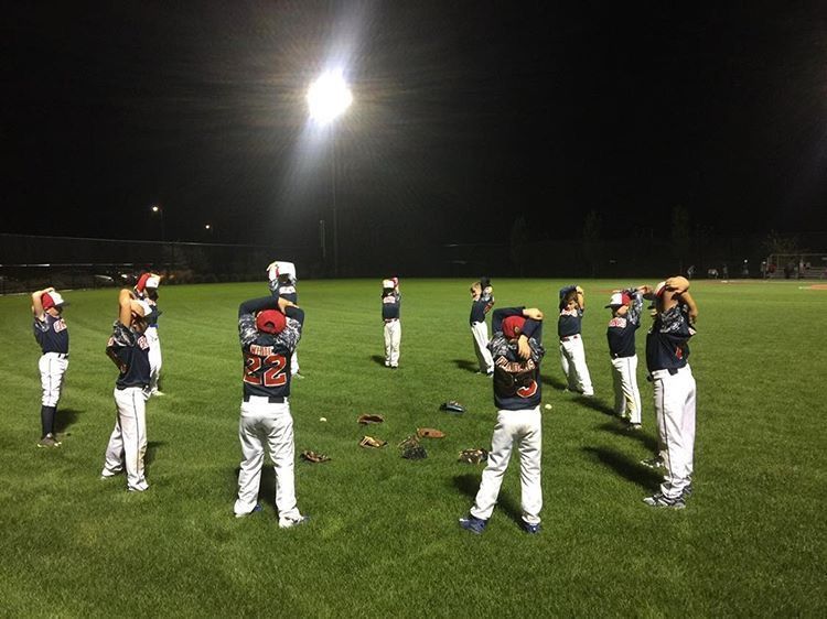 North Shore Giants players stretching during an evening baseball game.