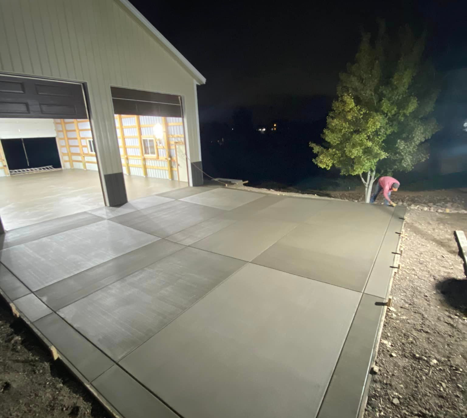 Concrete driveway beside a lit garage at night