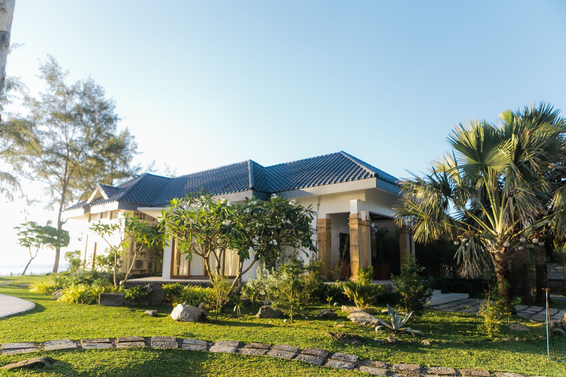 A house with a blue roof is surrounded by trees and grass.
