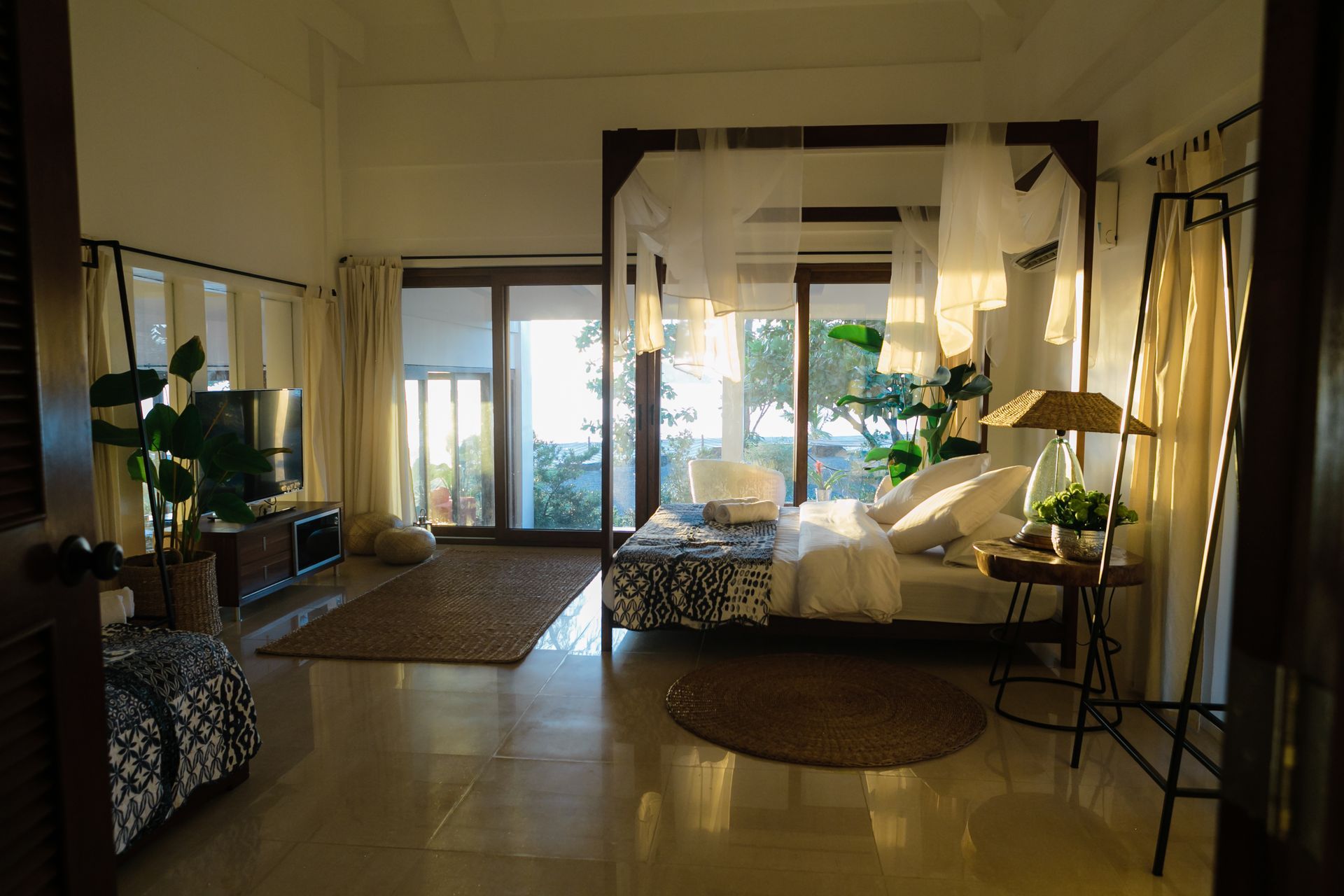 A bedroom with a bed , television , and sliding glass doors.