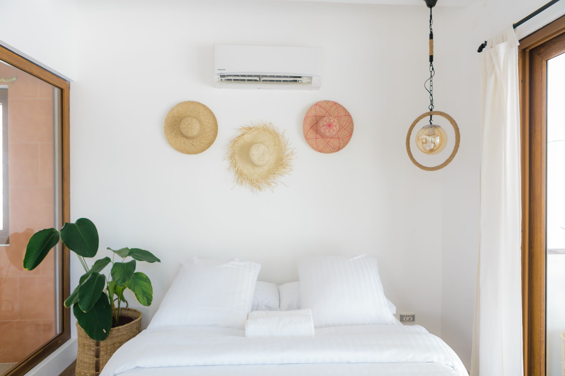 A bedroom with a bed and straw hats on the wall.
