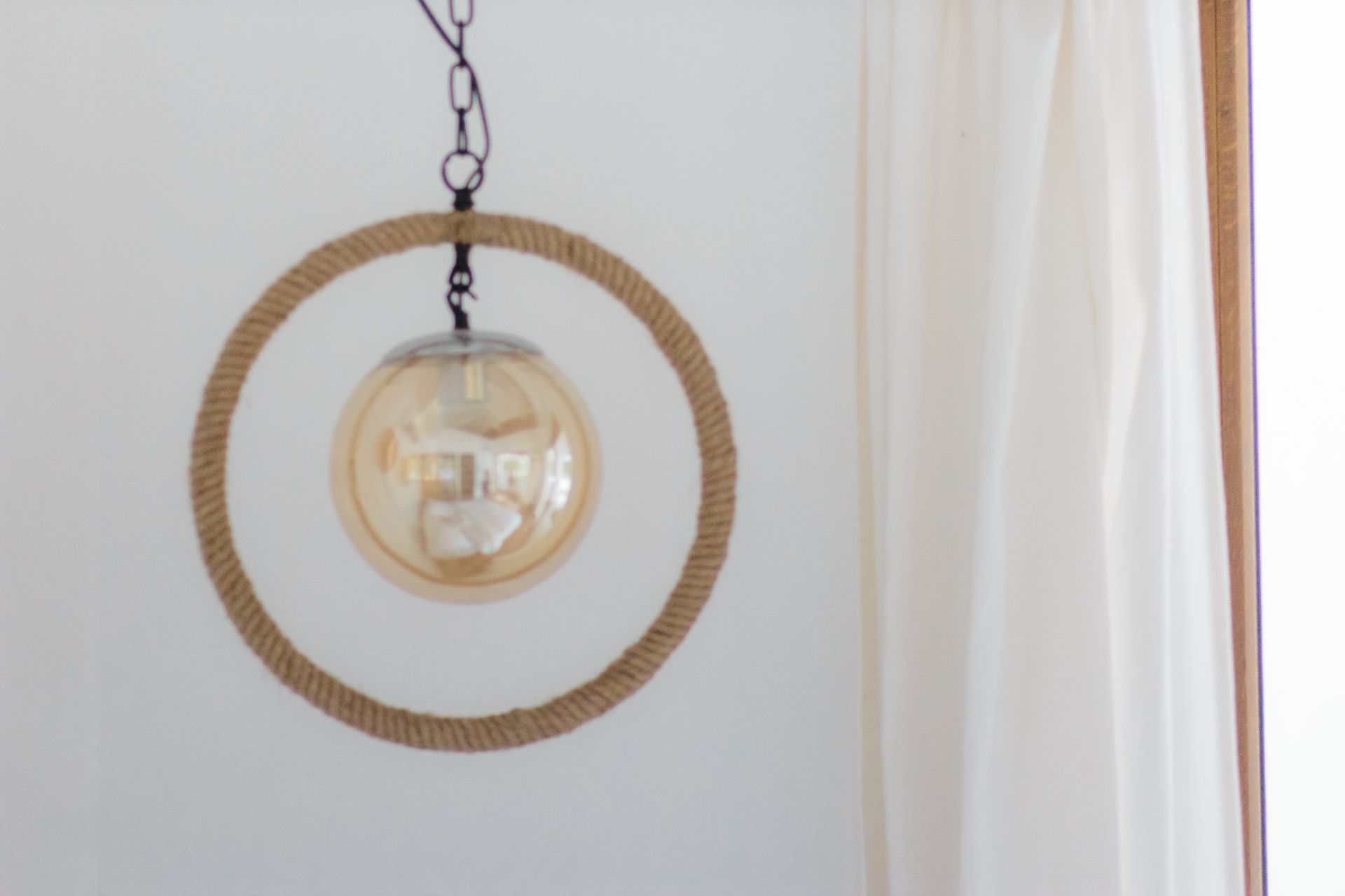 A light bulb is hanging from a rope ring on a chain.