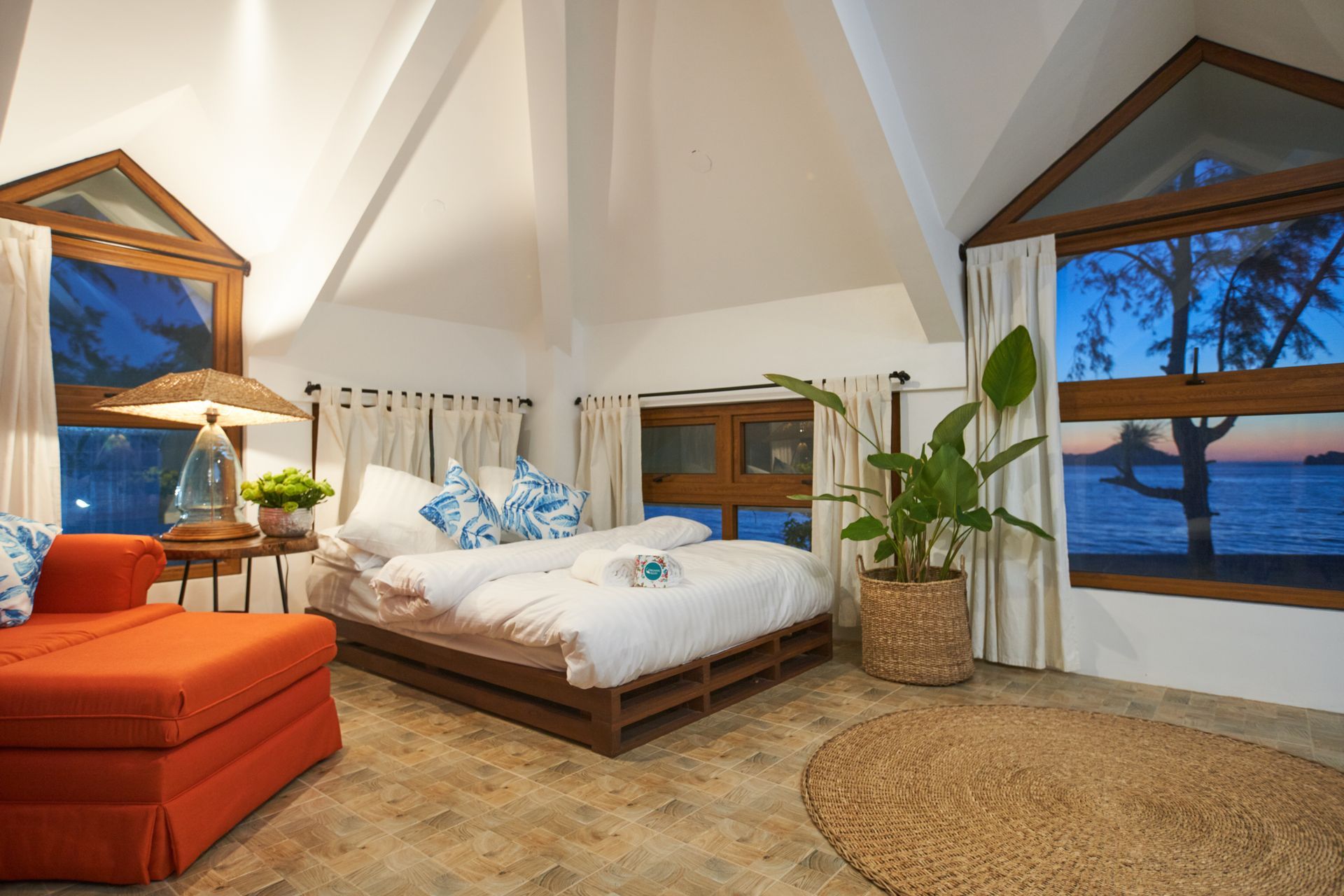 A bedroom with a bed and a couch with a view of the ocean.