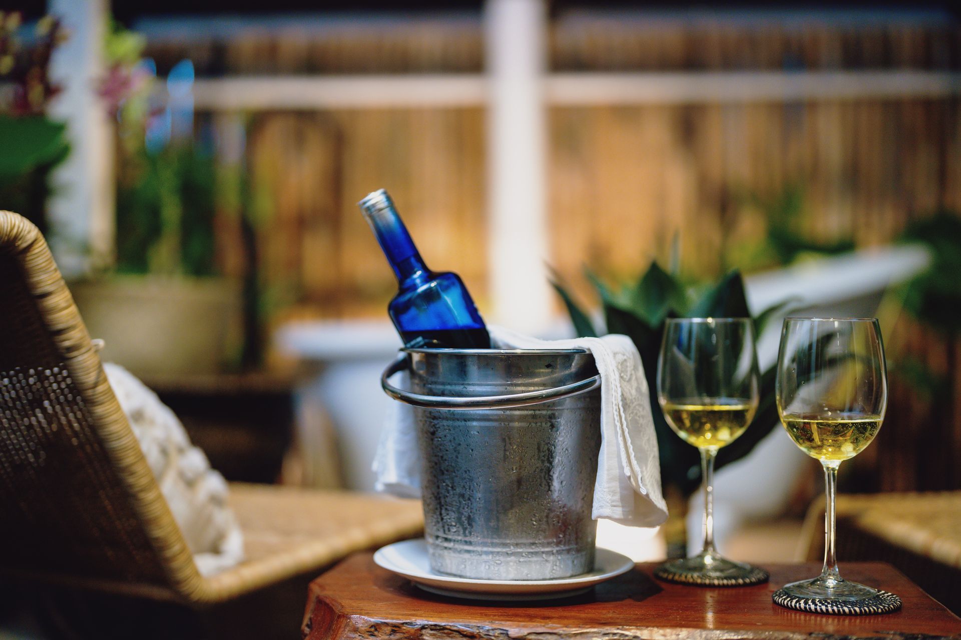 A bucket of wine and two glasses of wine on a table.