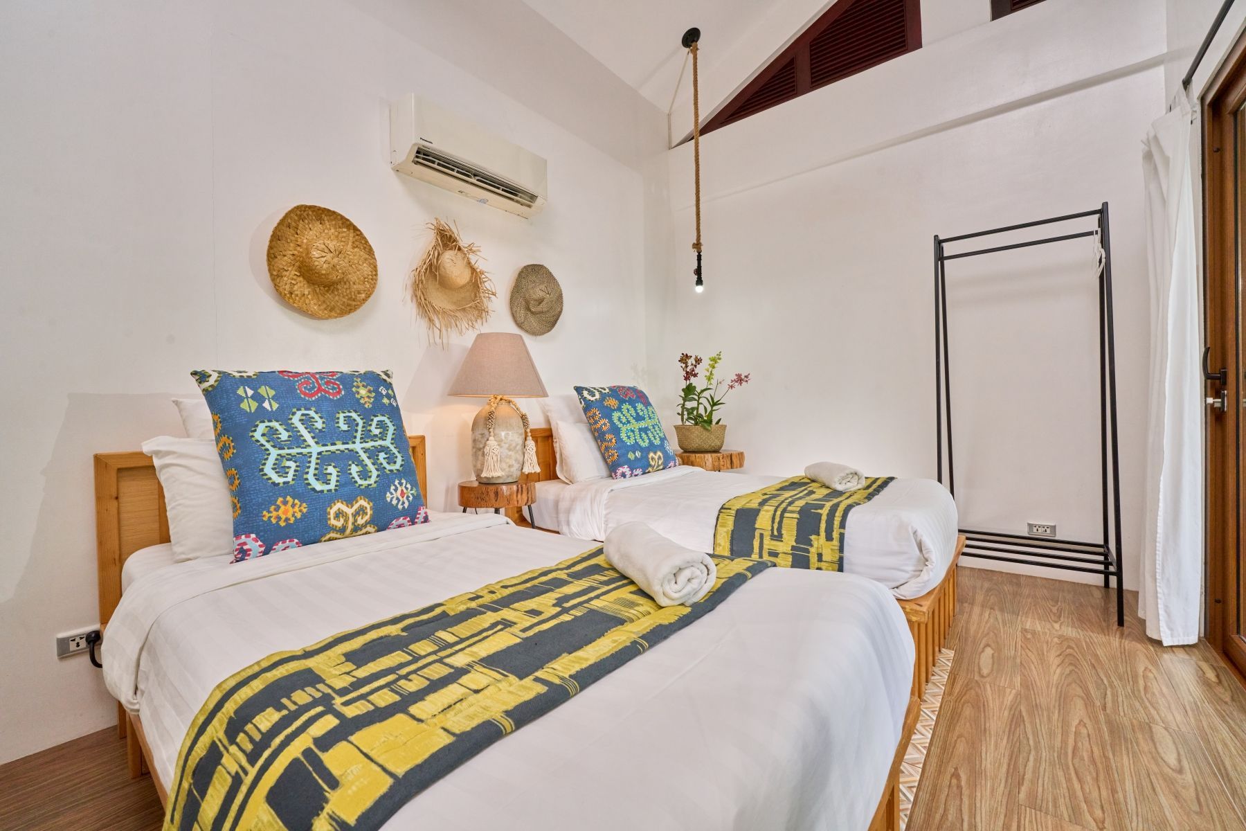A bedroom with two beds and a clothes rack.