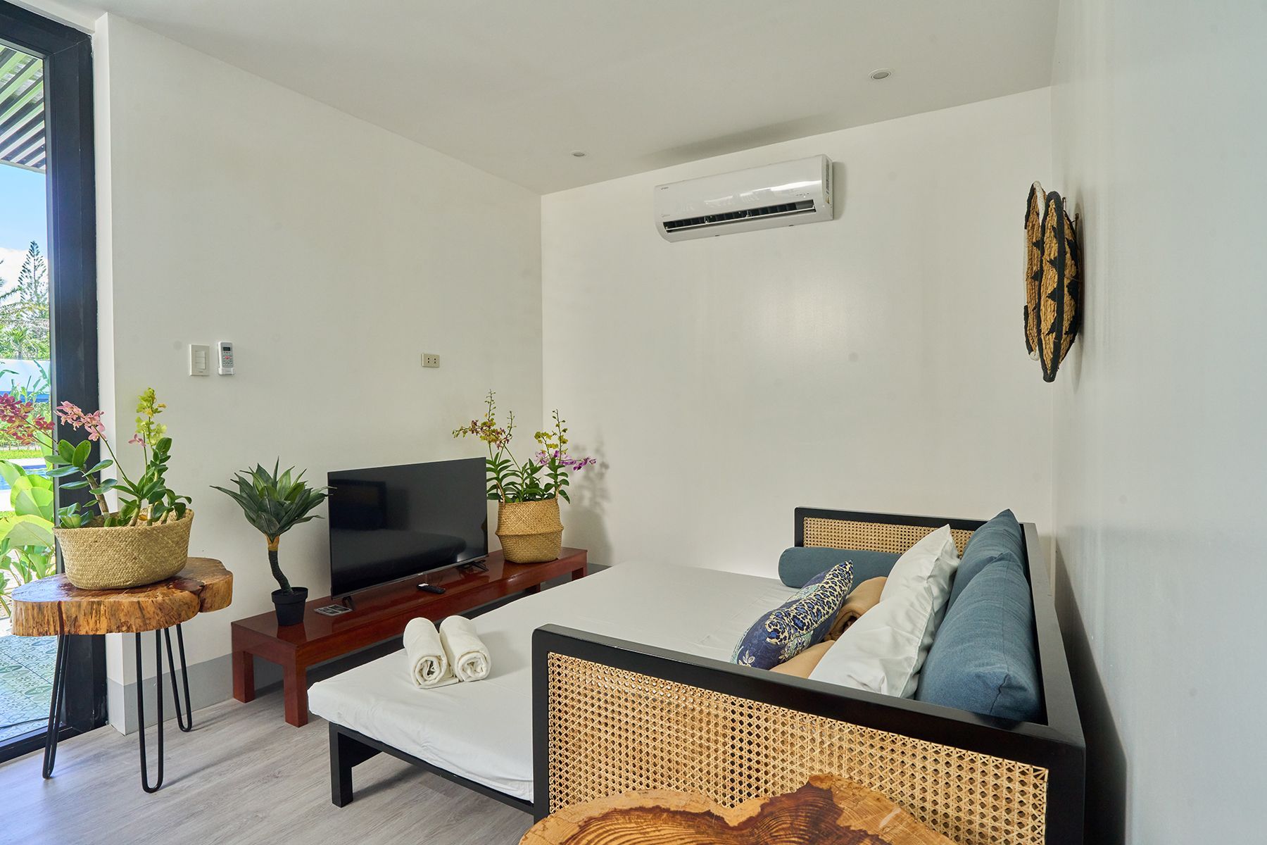 A living room with a bed , couch , television and air conditioner.