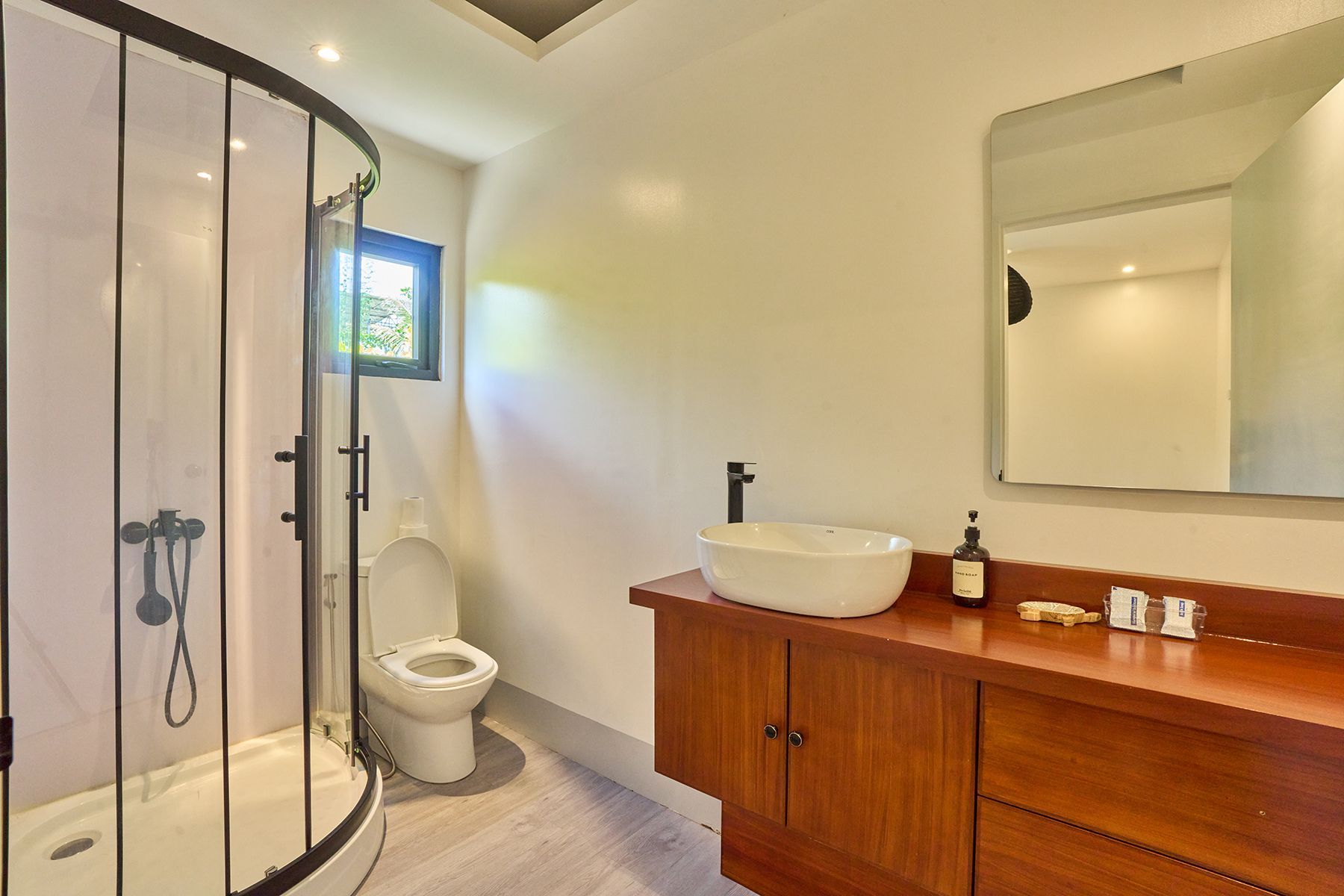 A bathroom with a toilet , sink , shower and mirror.