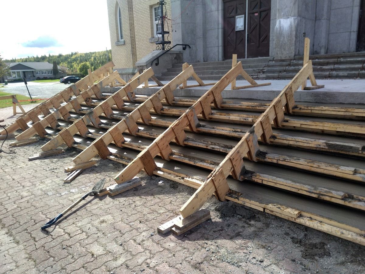 Des rampes en bois ont été installées temporairement sur les escaliers en pierre d'un bâtiment, probablement pour des raisons d'accessibilité.
