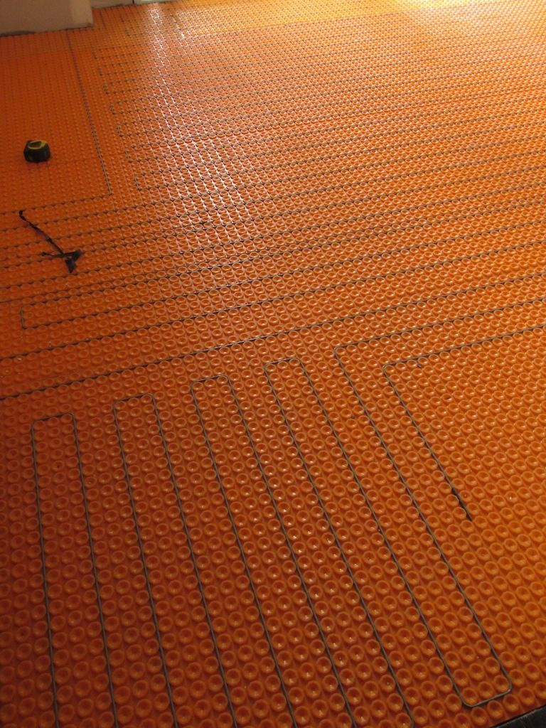 Système de chauffage au sol orange avec tubes noirs installés.