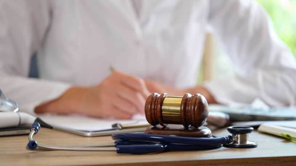 A lawyer is sitting at a desk with a stethoscope and a judge 's gavel.