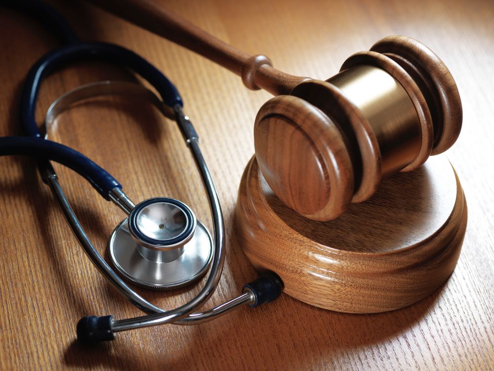 A stethoscope sits next to a wooden gavel on a wooden table