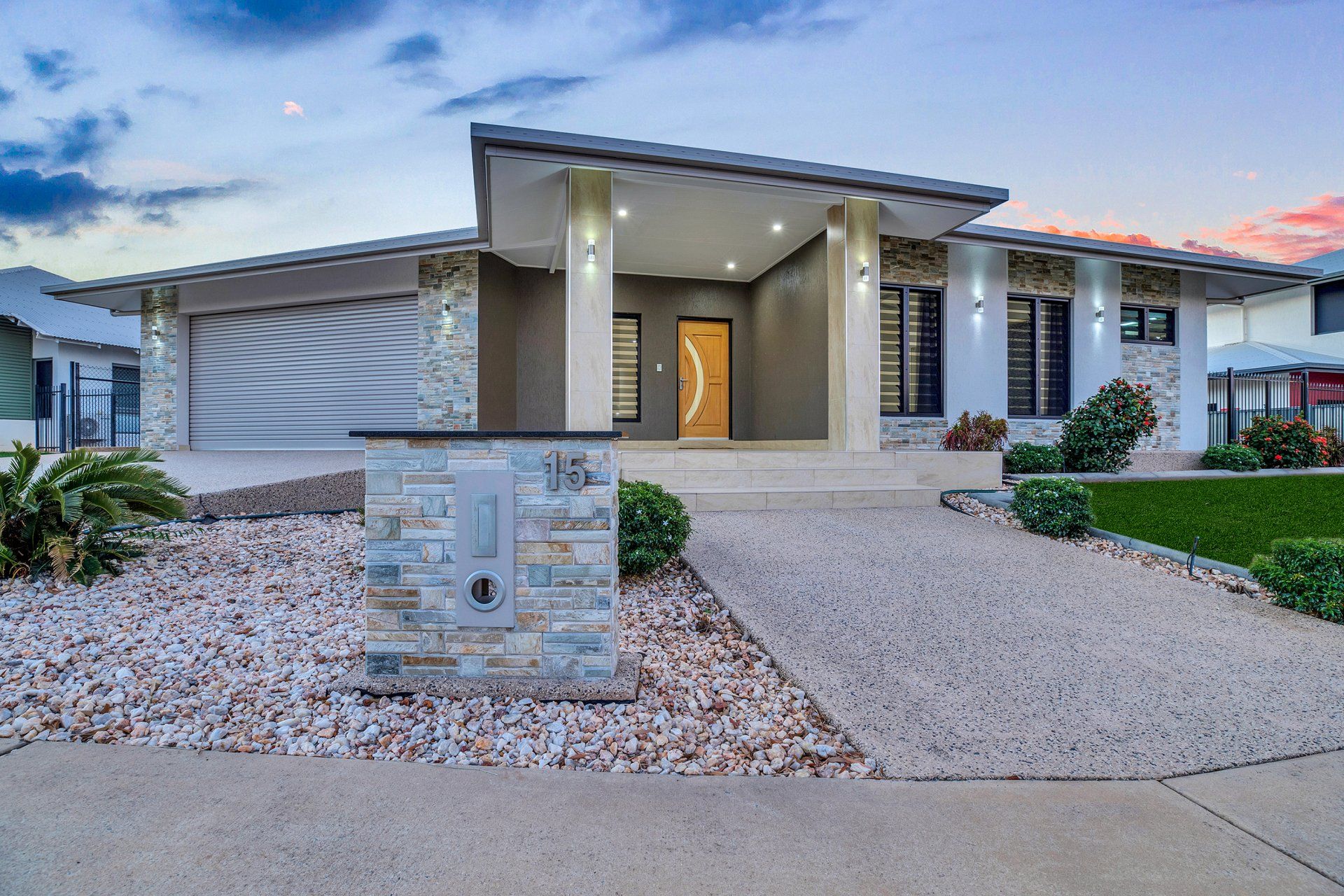 A large house with a concrete driveway and gravel in front of it