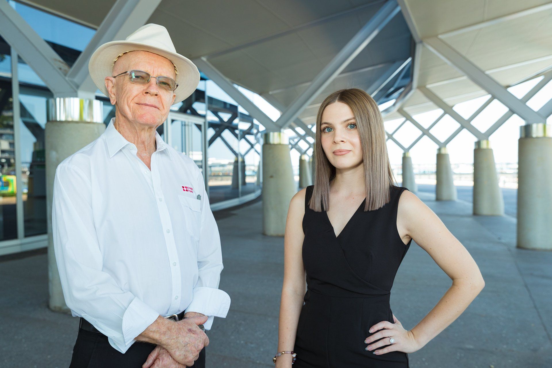A man and a woman are standing next to each other in front of a building.