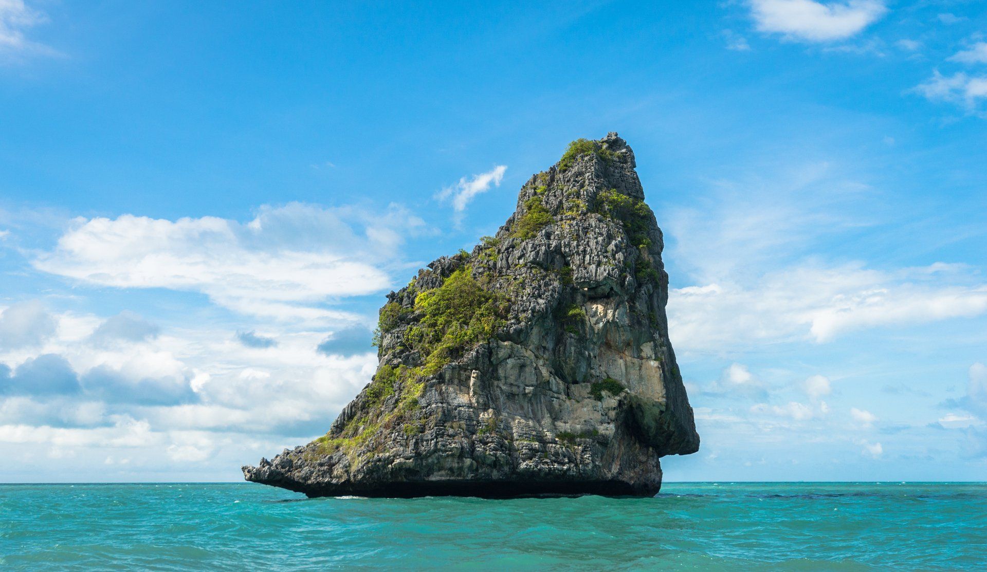 There is a large rock in the middle of the ocean.