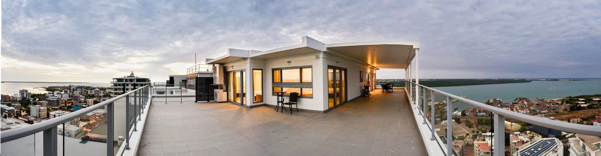 A large balcony with a view of the ocean and a city.