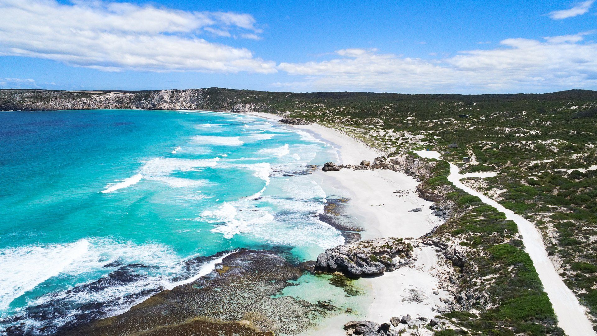 An aerial view of a beach with a road leading to it.