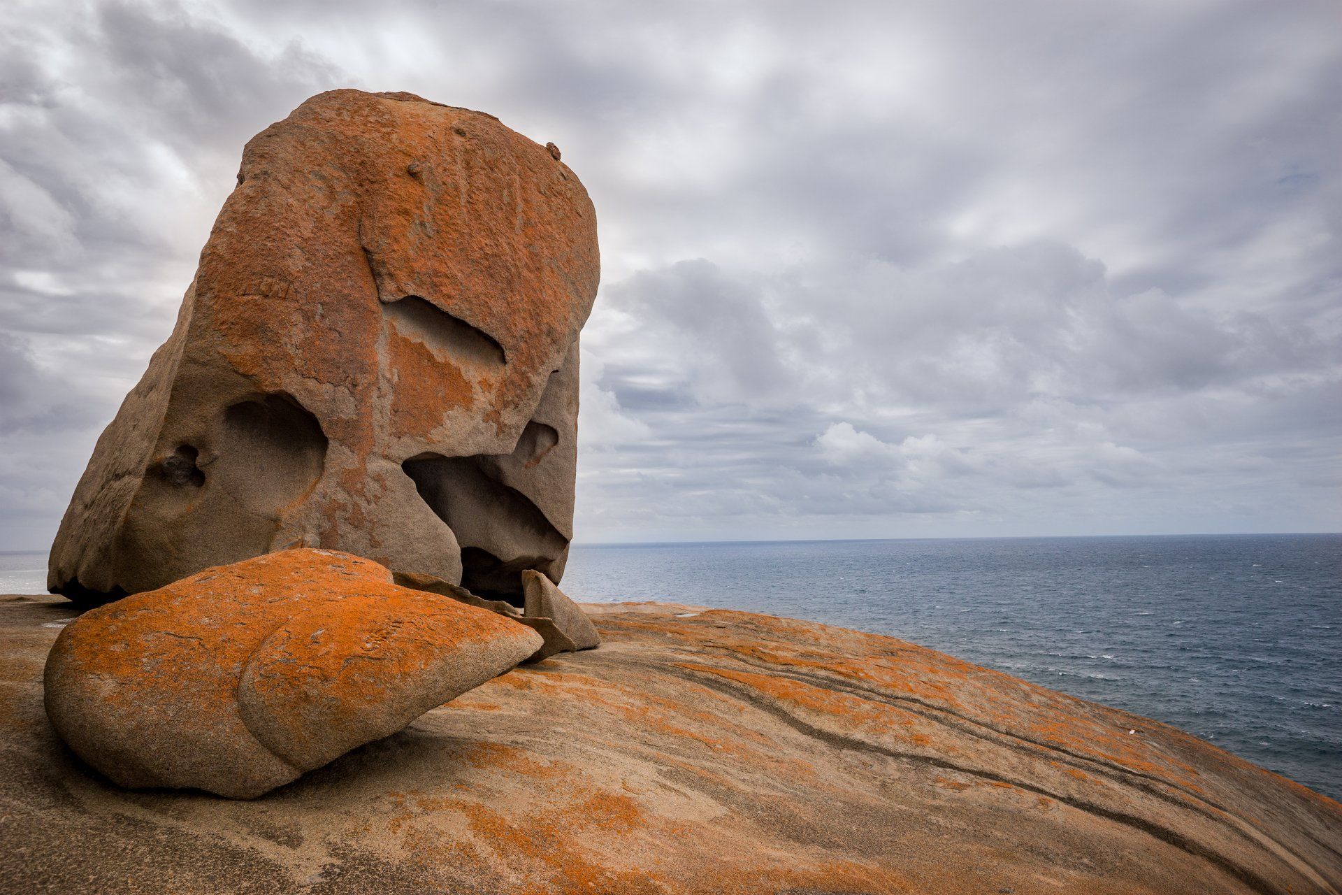 A large rock sitting on top of a cliff overlooking the ocean.