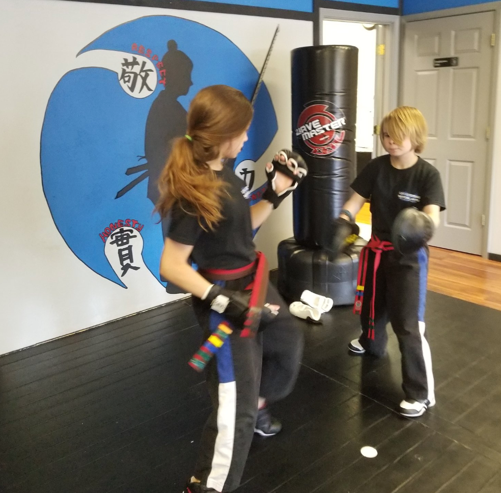 Two people are practicing martial arts in a gym