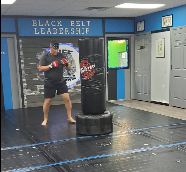 A man stands in front of a sign that says black belt leadership