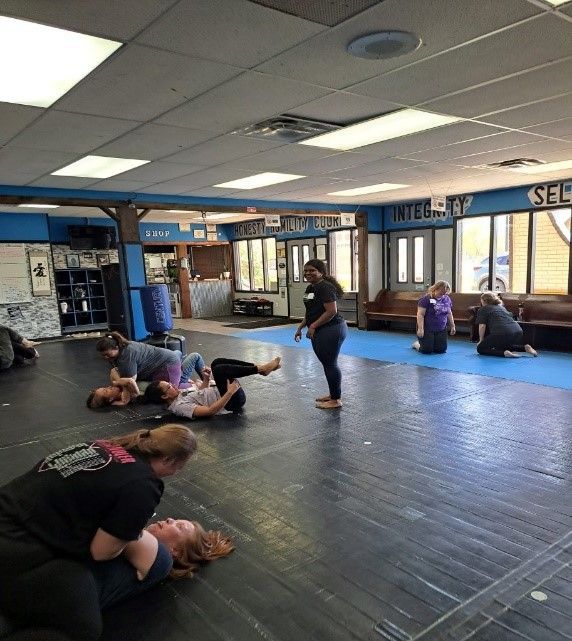 A man and a woman are practicing self defense in a gym.