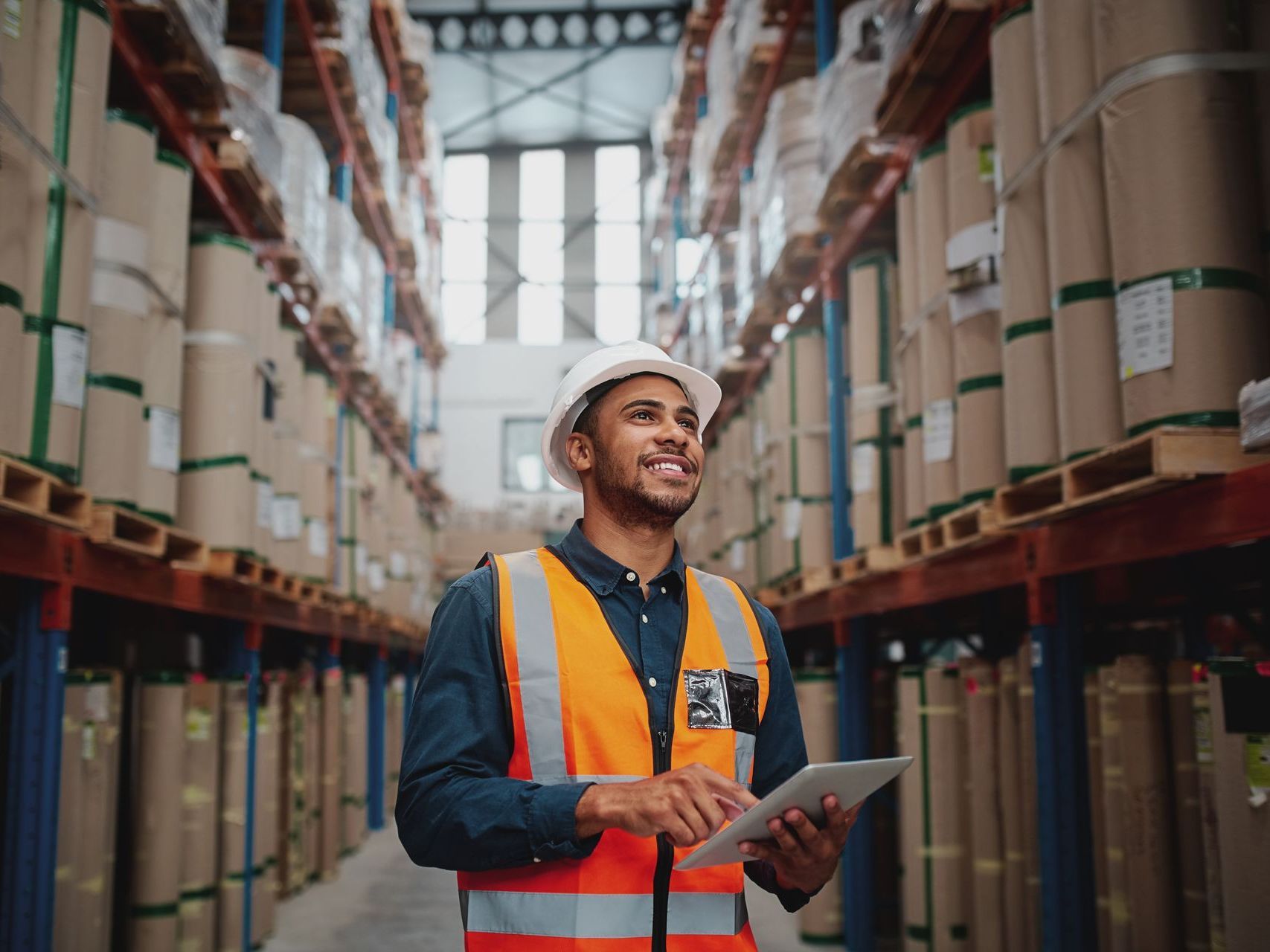 a man is standing in a warehouse holding a tablet .