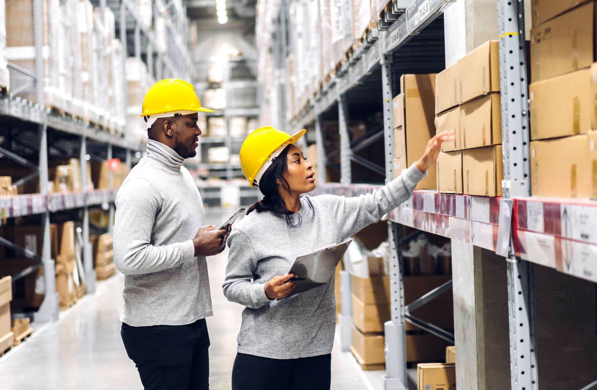 a man and a woman are standing in a warehouse looking at boxes .
