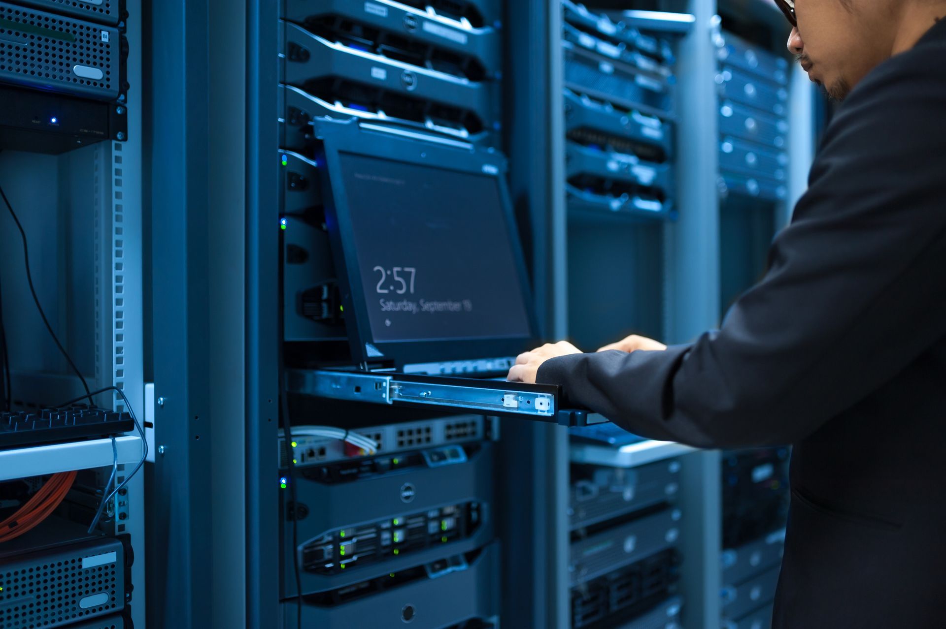 a man is working on a laptop in a server room .