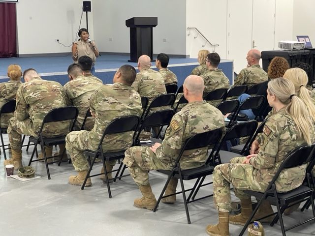 a group of soldiers are sitting in chairs listening to a speaker