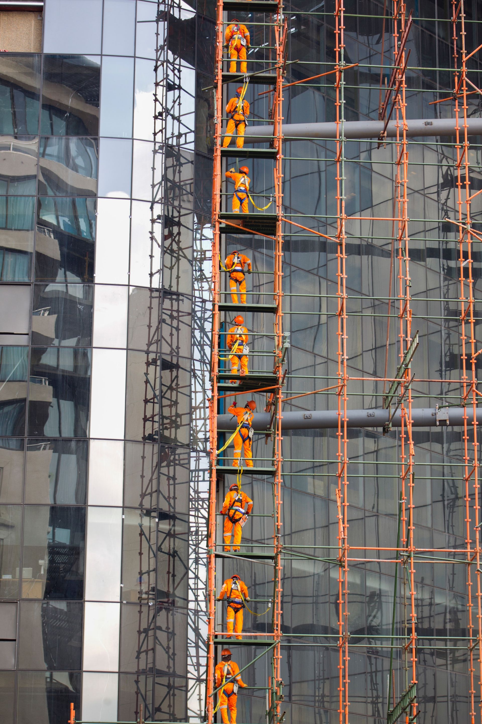 Construction crew on a scaffold wearing orange construction gear