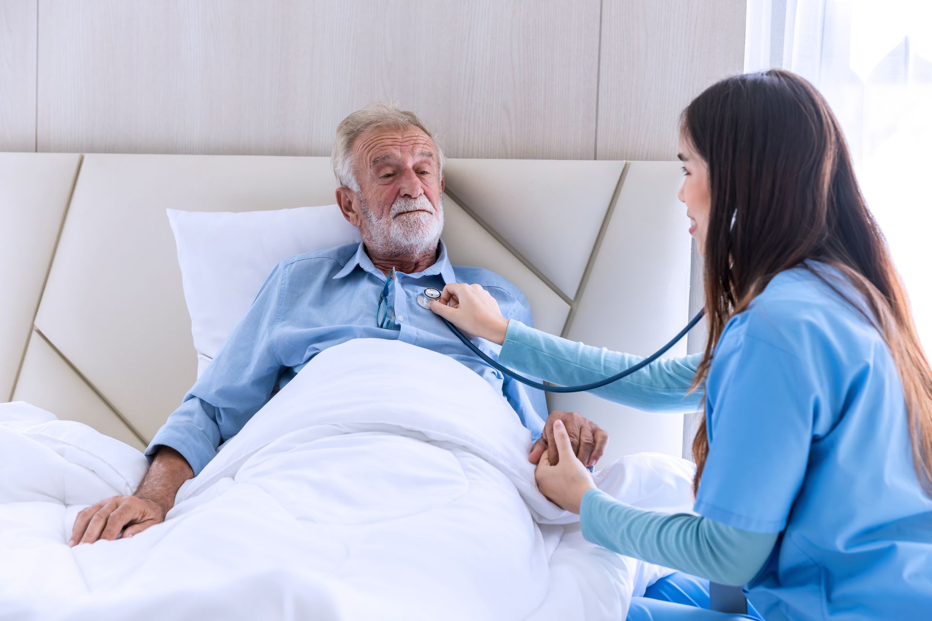 Nurse using stethoscope on patient in bed.