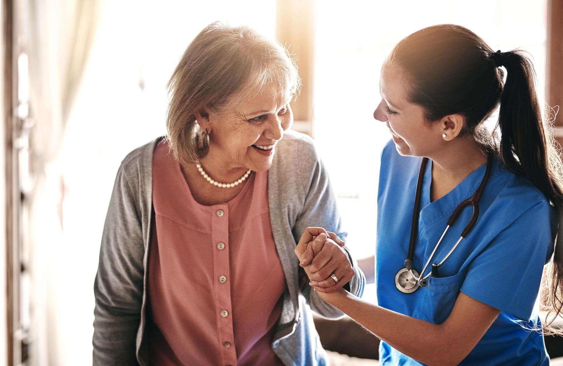 Nurse helps a smiling elderly person walk indoors.