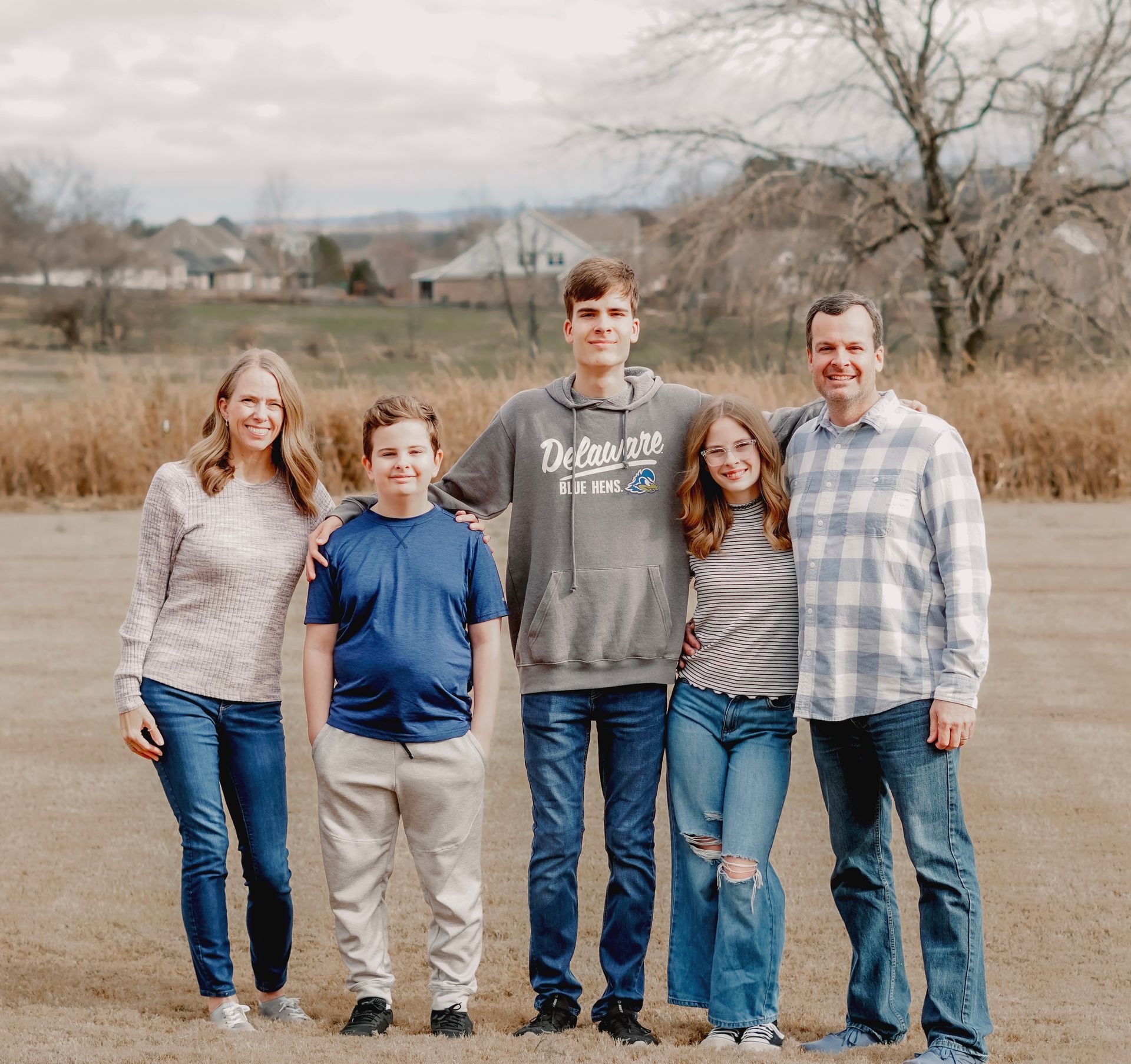 A family posing for a picture in front of a tree.