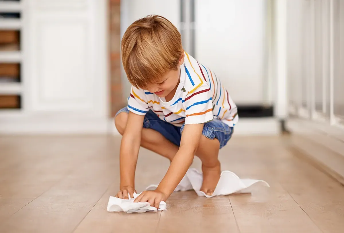Child wiping up a spill off waterproof laminate kitchen flooring.