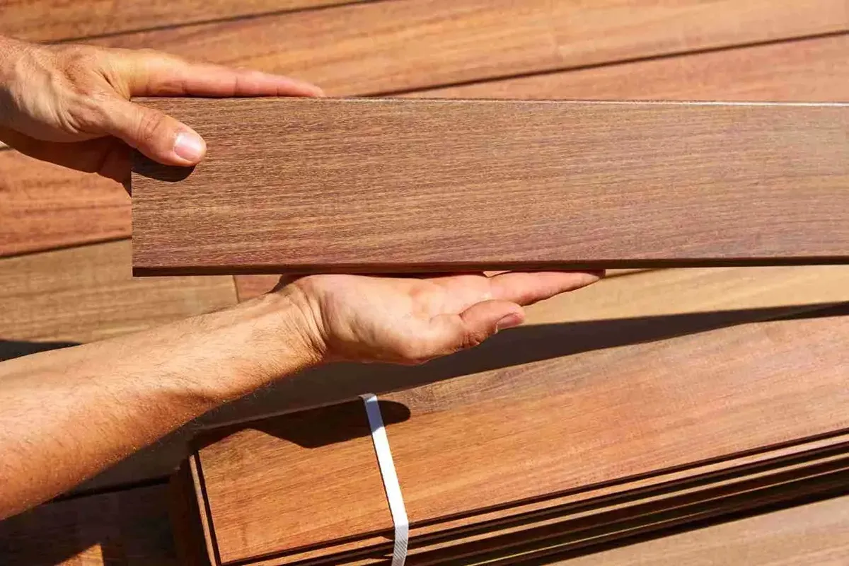 Closeup of someone holding a hand scraped hardwood flooring plank.