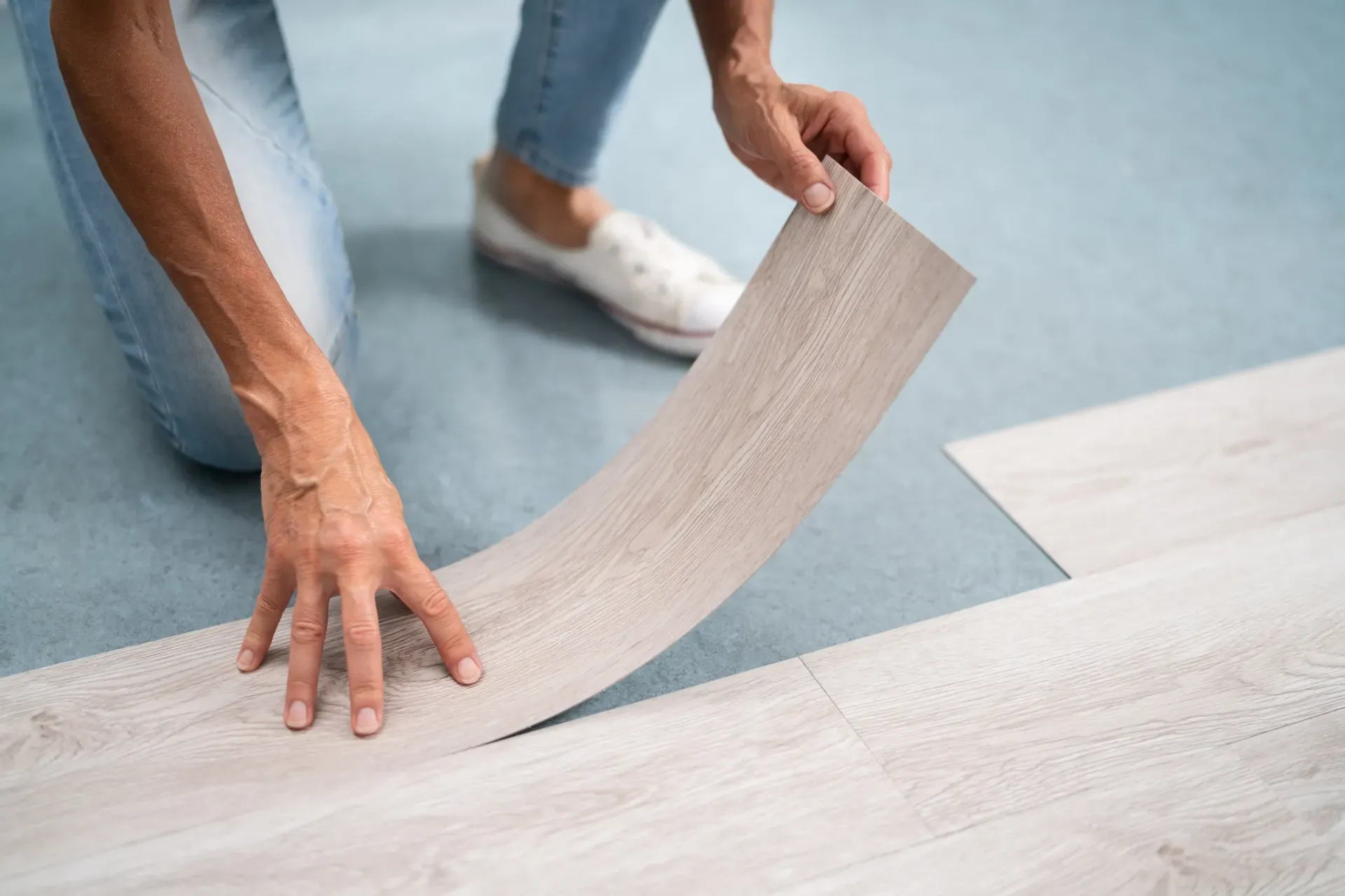 Person installing peel and stick flooring showing how flimsy and thin it really is.