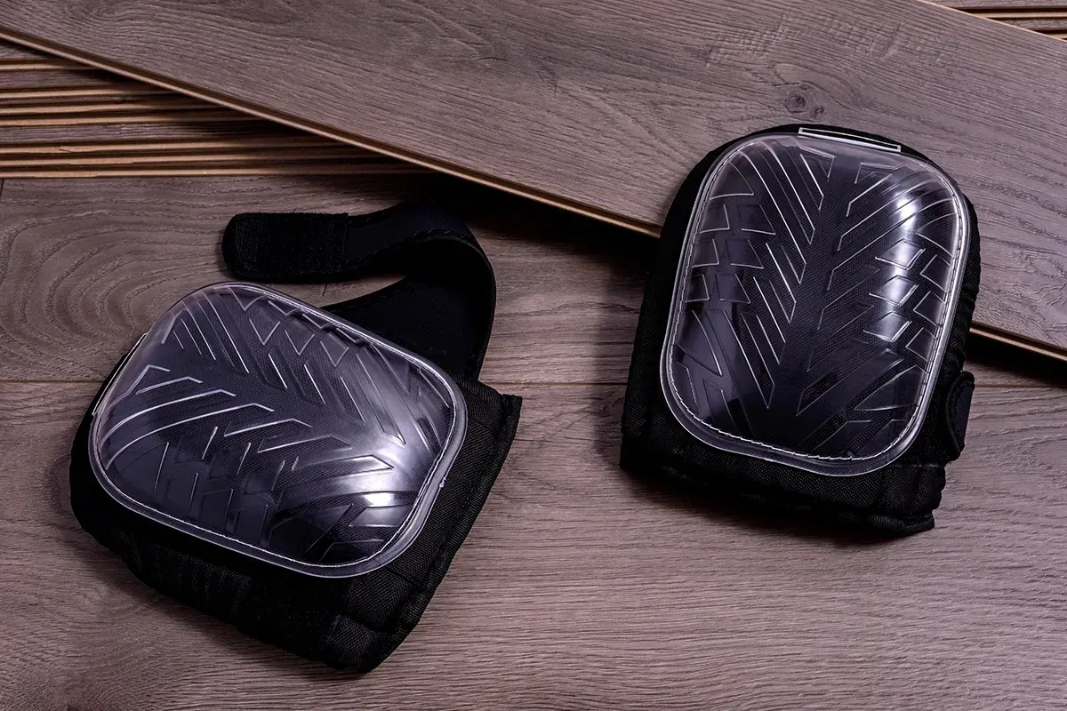 Knee pads sitting on top of flooring planks.