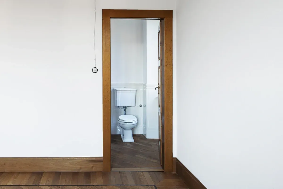 Laminate flooring in small bathroom matched to the flooring in hallway to create a better flow between two rooms.