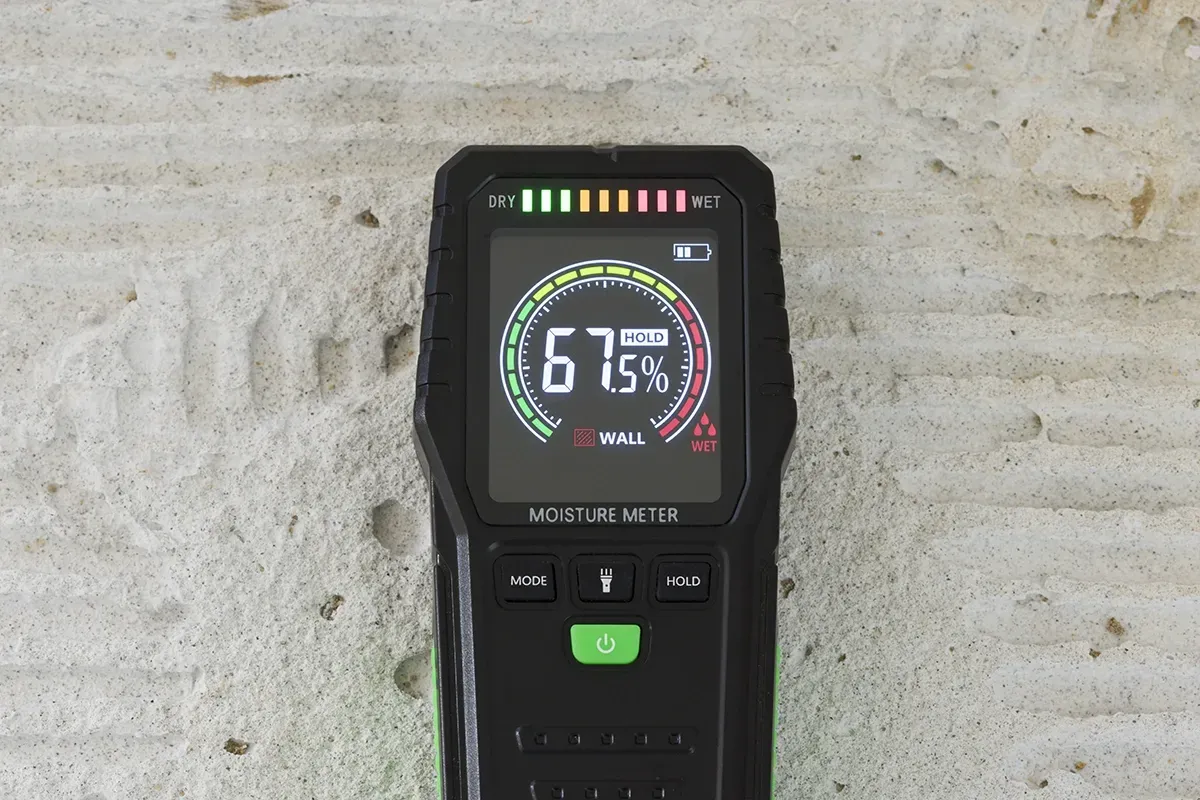 Moisture meter showing a a reading of 67.5% indicating a wet surface.