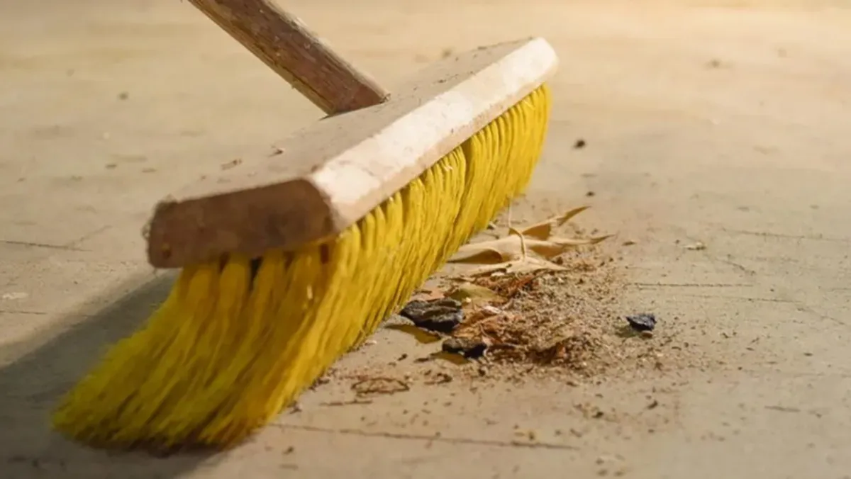 Push broom sweeping debris from wooden subfloor