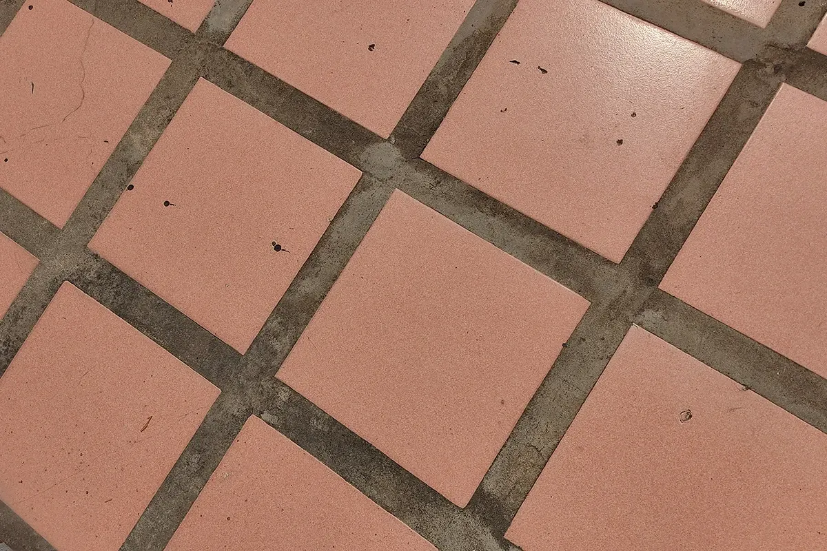 Red tile flooring with wide uneven grout lines.