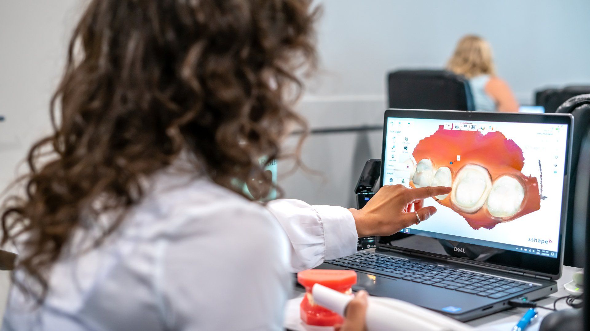 A woman is sitting at a desk using a laptop computer.