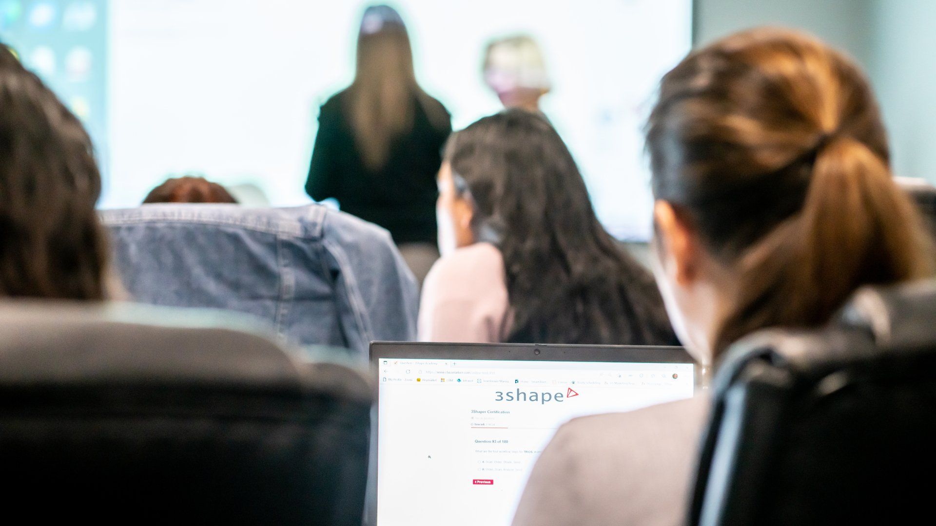 A group of people are sitting in front of a laptop computer.