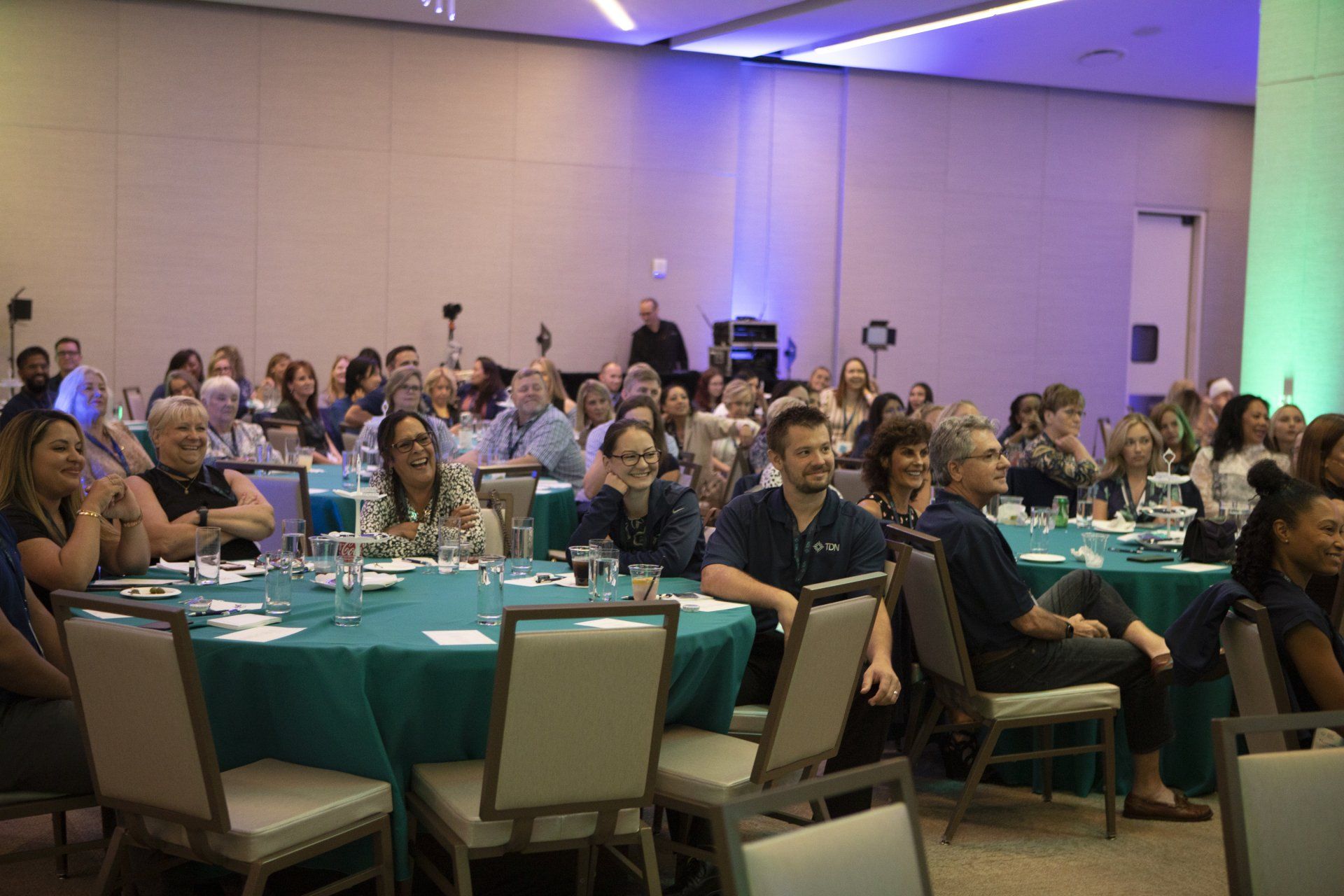A large group of people are sitting at tables in a conference room.