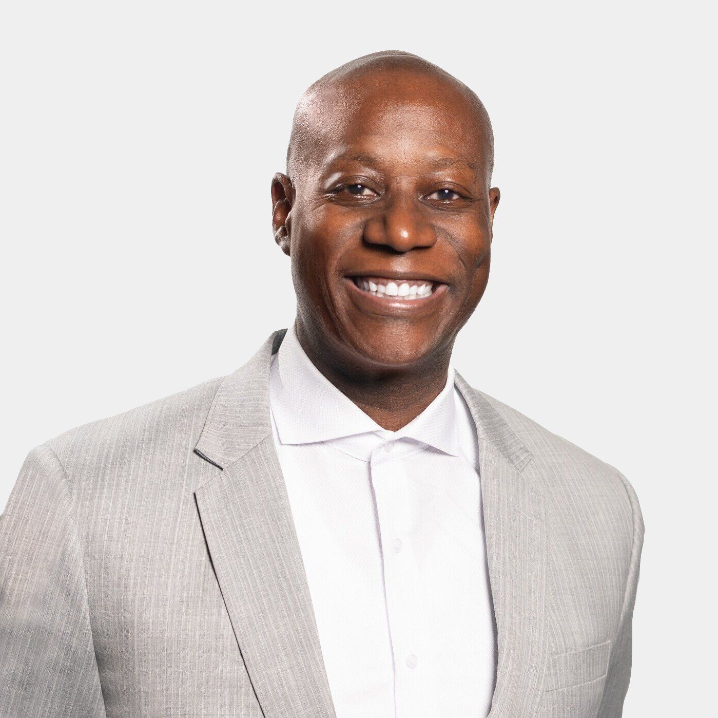A man in a suit and white shirt is smiling for the camera.